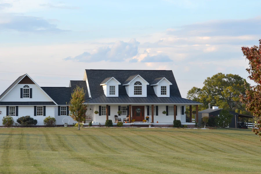 White farmhouse with a wrap-around porch on a wide green lawn